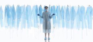 A woman in blue scrubs standing in front of a bunch of blue hangers.